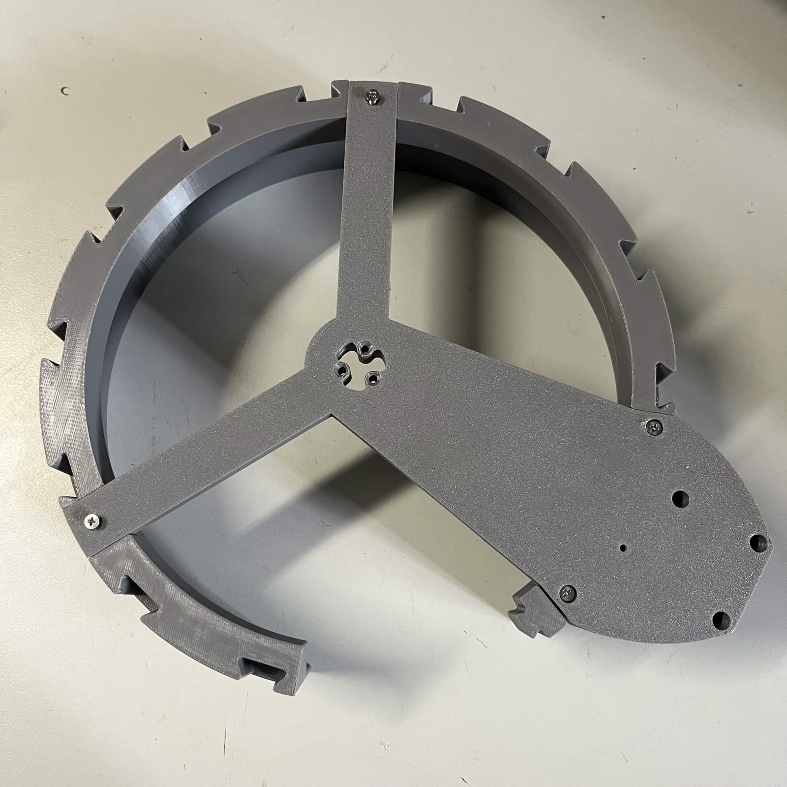 The stator ring seen from underneath with the three-armed NEMA bracket fastened across it, each arm reaching the rim