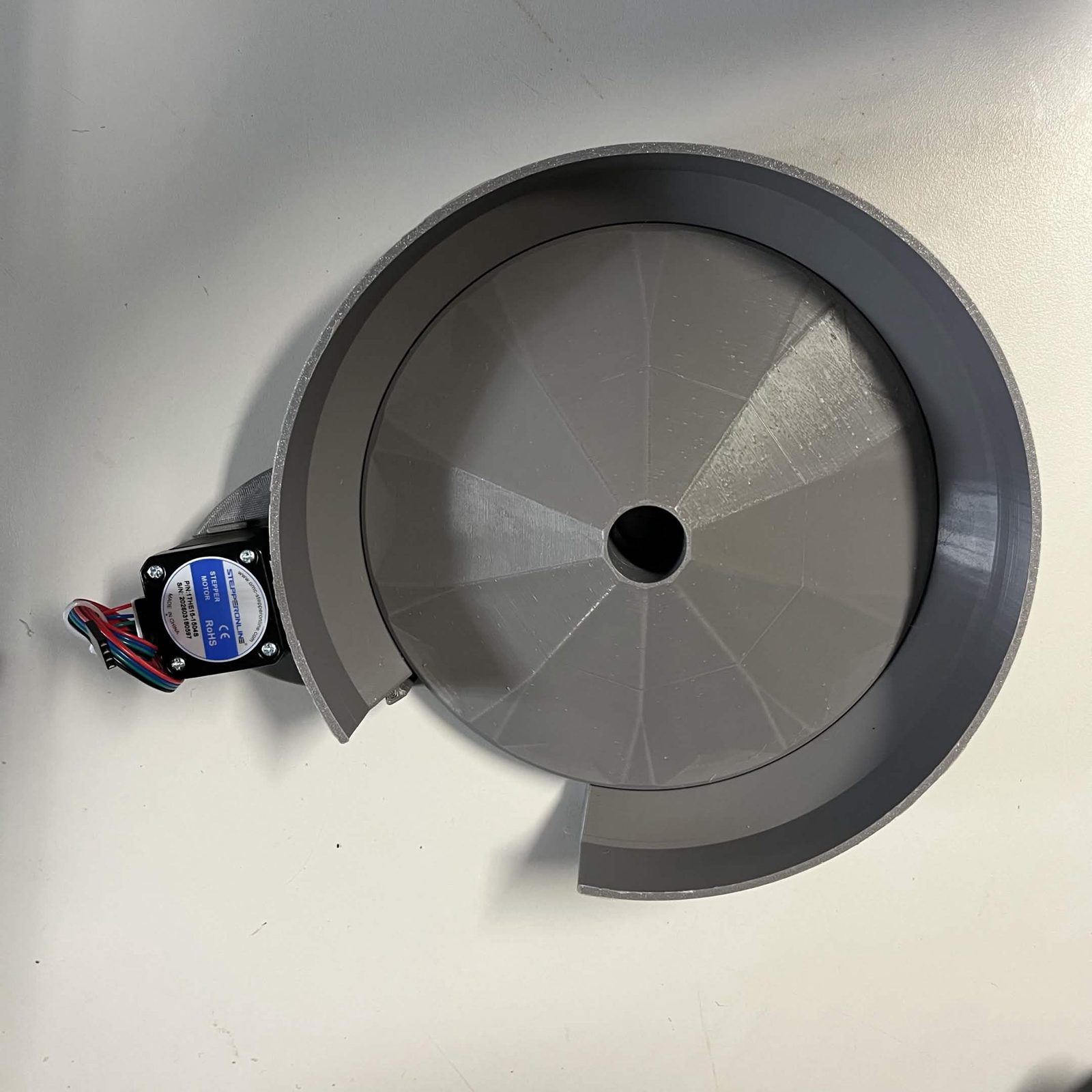 A C-channel from above on a plain surface: the faceted rotor sitting down in the stator ring, with the stepper motor and its lead standing off one side