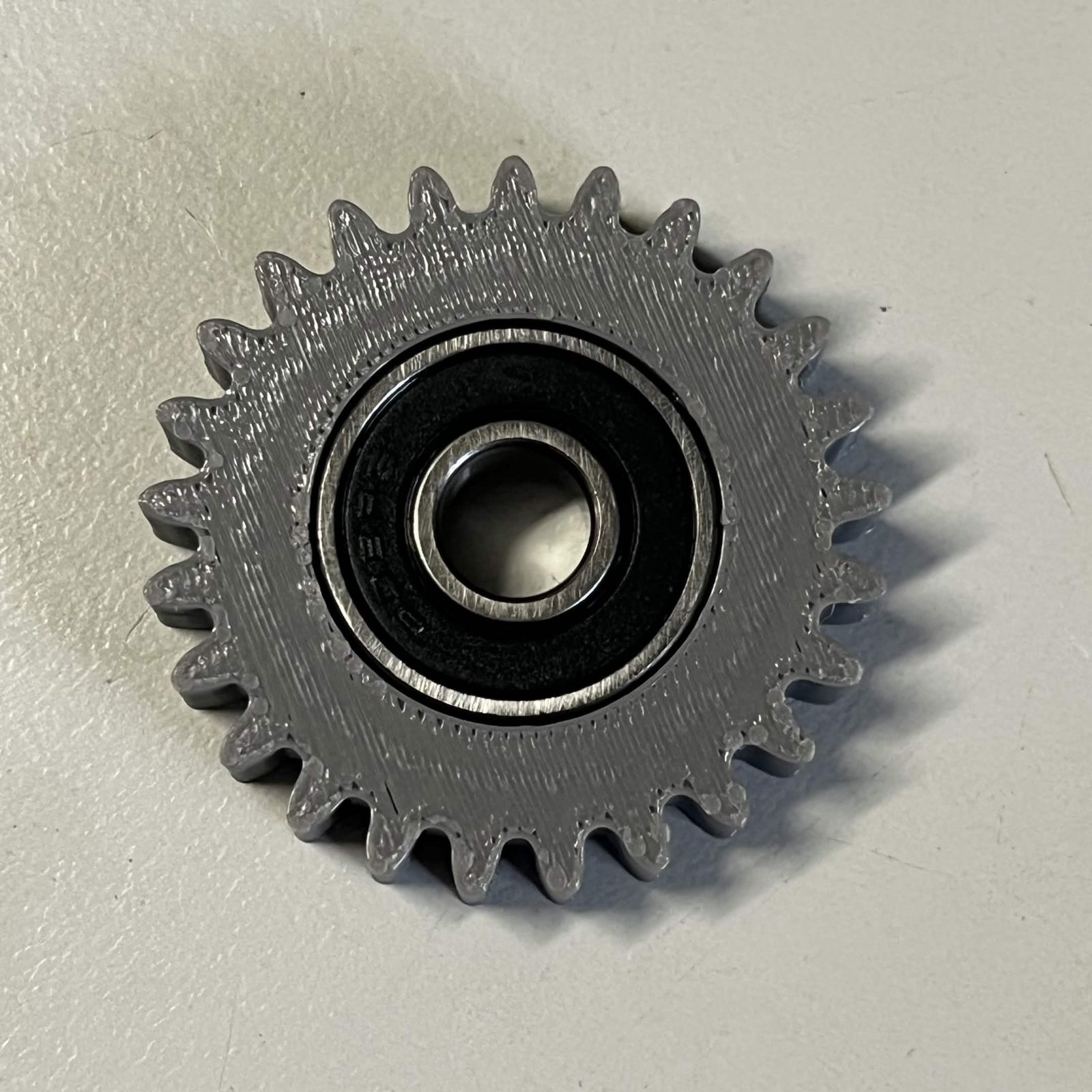 The 24-tooth idler gear with a black-sealed 608 bearing pressed into its centre, seen from above