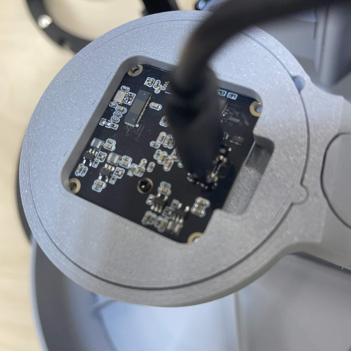 Looking down on a finished classification lamp: the grey cover with its square opening, the 4K camera board seated in the clasp inside it, and its cable plugged into the top of the board