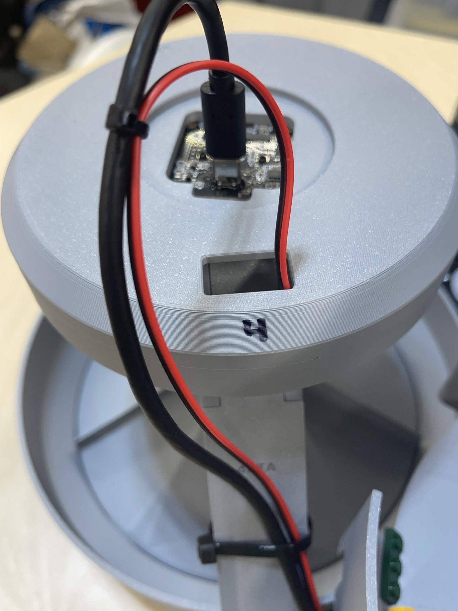 The classification lamp, marked 4, from a lower angle: the camera cable standing up out of the board, the red and black lamp leads looped over the cover and cable-tied clear of it, and the rectangular slot in the cover below