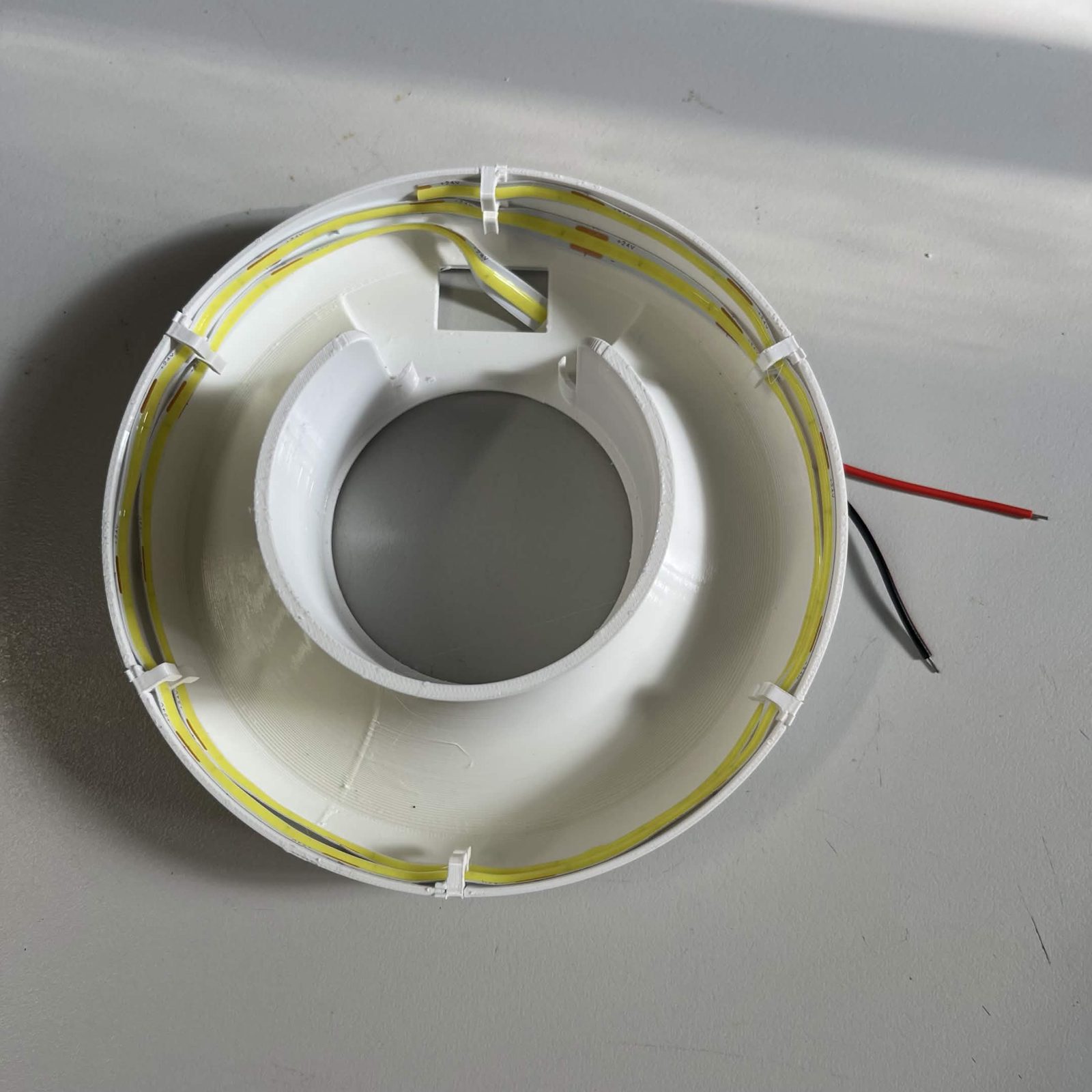 Both turns of strip in the skirt, one above the other, film gone, with the red and black leads leaving the reflector at one side
