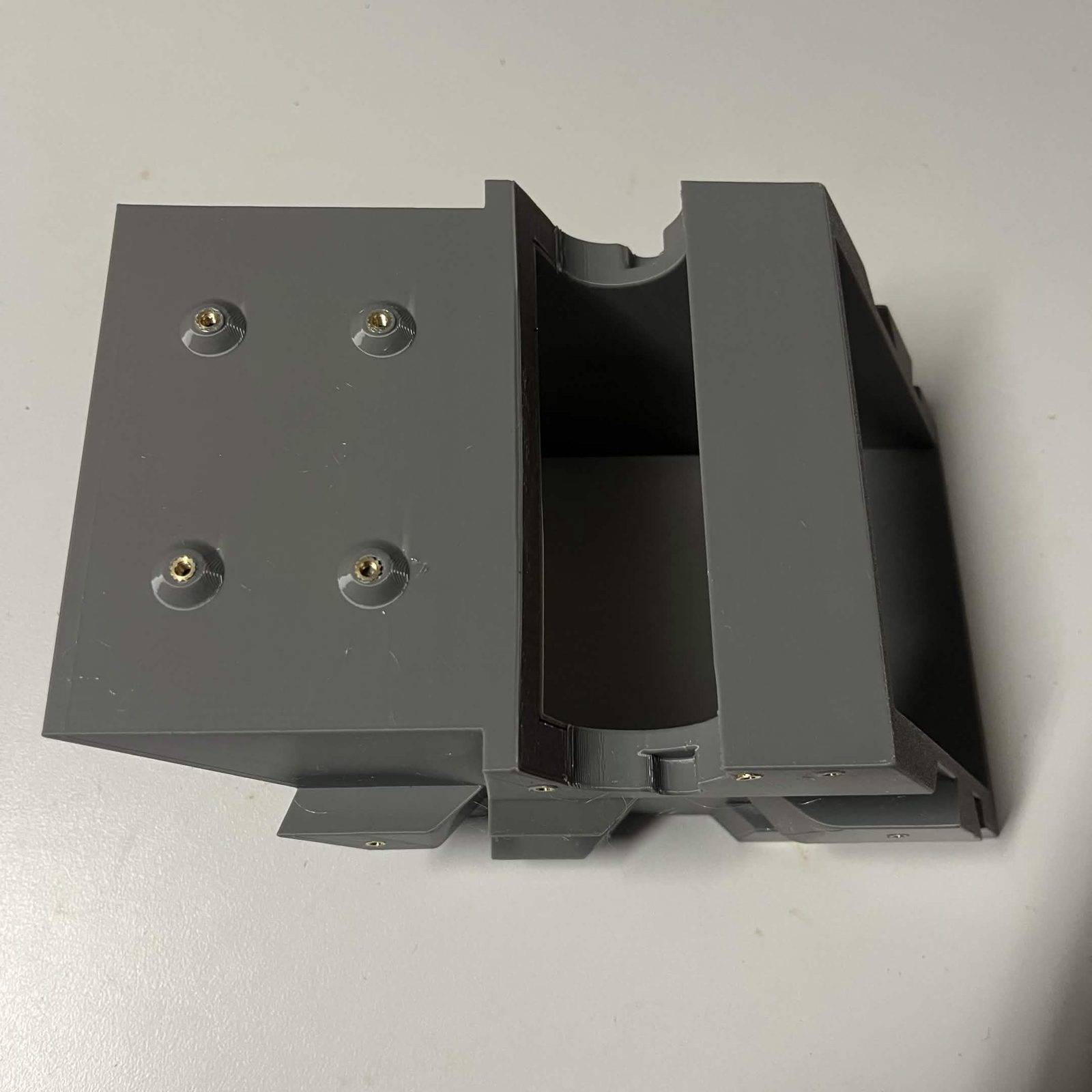The rear panel of the chute core seen from above, four brass heat inserts in a square, with the curved channel of the core beside it