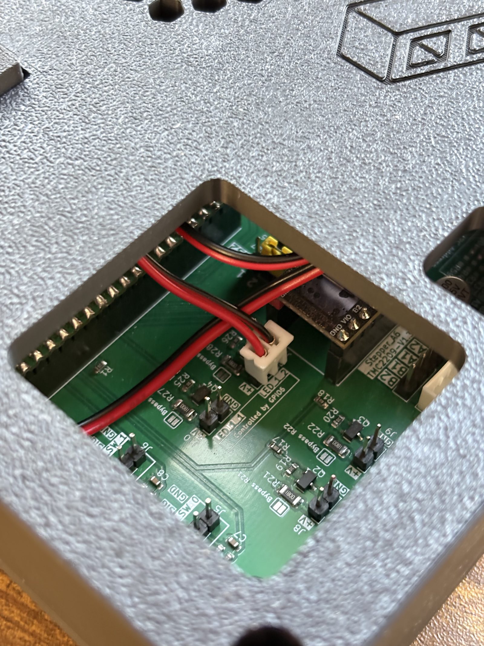 Looking down through the cover's corner cutout at the board below, where the fan's red and black lead is plugged into the two-pin connector silkscreened LED_1_2, with Controlled by GPIO6 printed beside it
