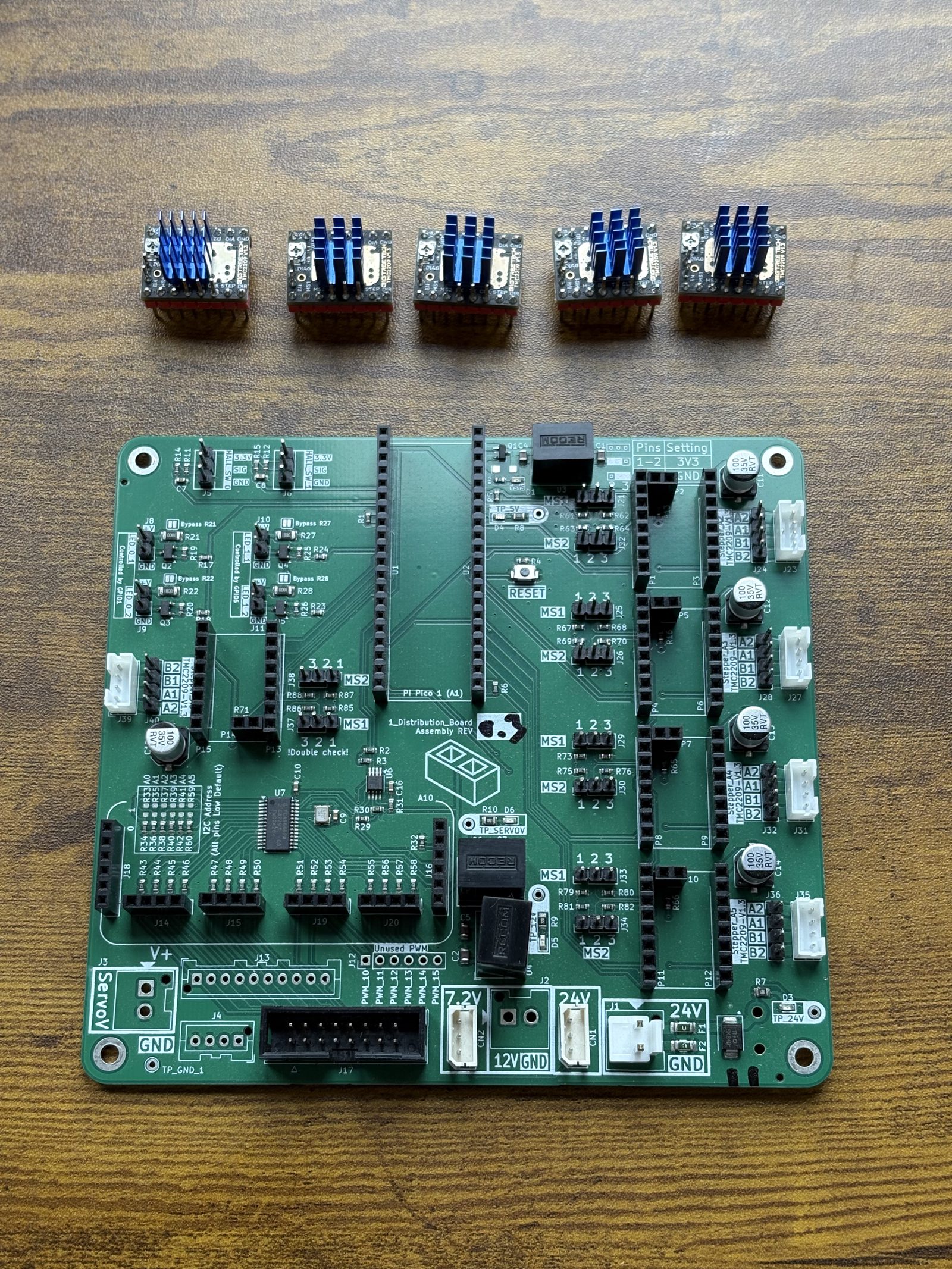 The bare green basically Embedded Control Board on a wooden bench with five blue-finned TMC2209 stepper driver modules laid out in a row above it