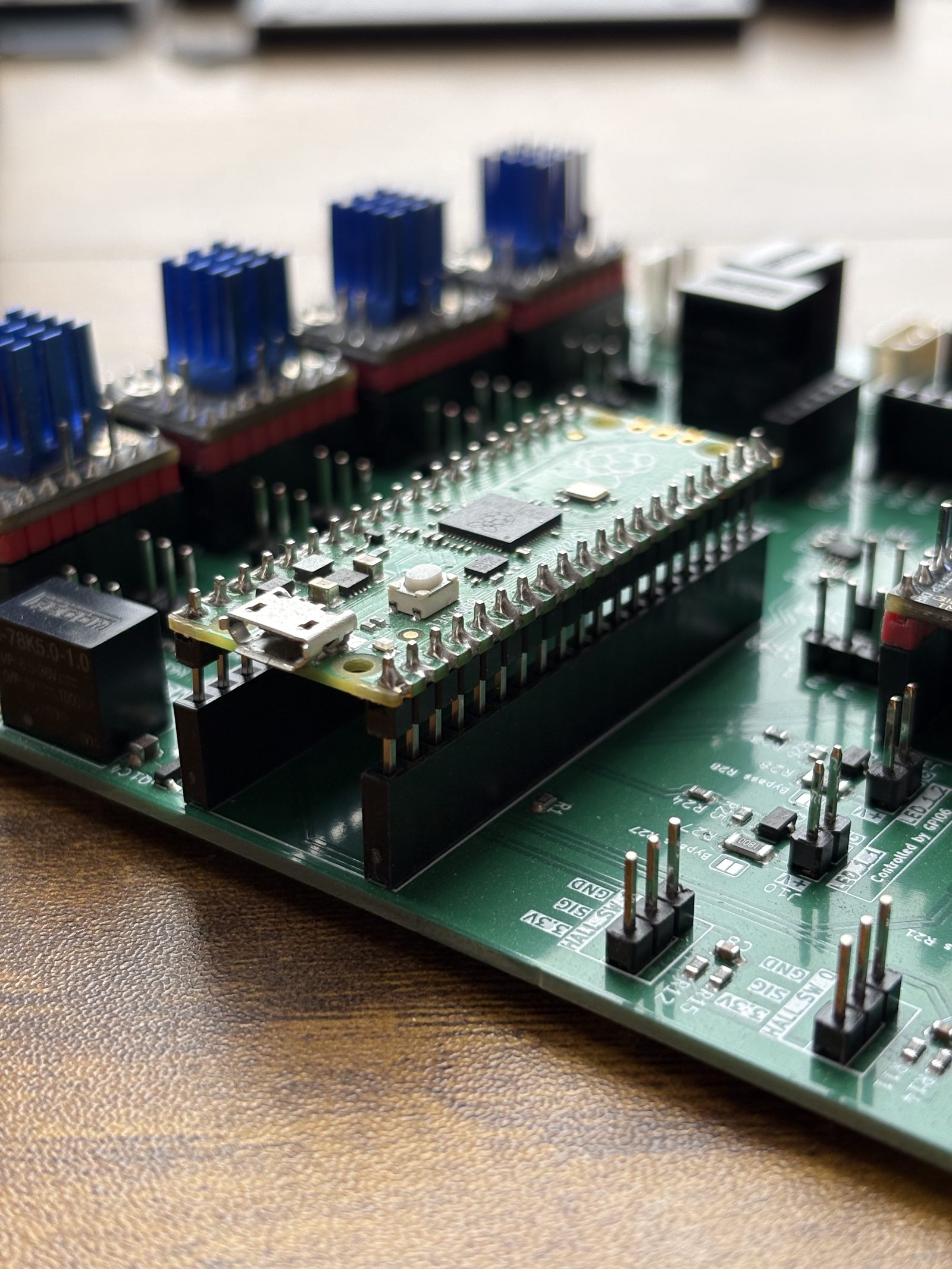A Raspberry Pi Pico held just above its two long header sockets on the control board, ready to be pushed down, with seated stepper drivers behind it