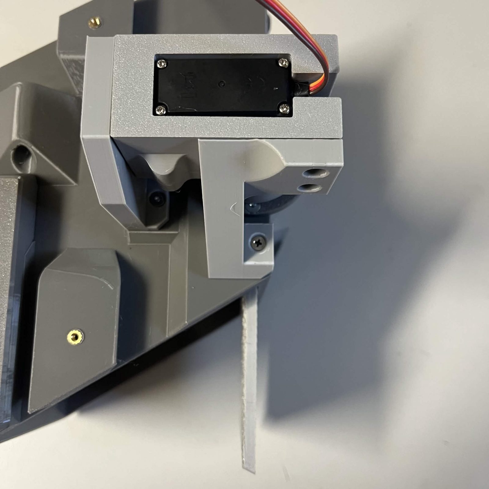 The same assembly from above, the servo in its bracket standing off the chute core with the door hanging below