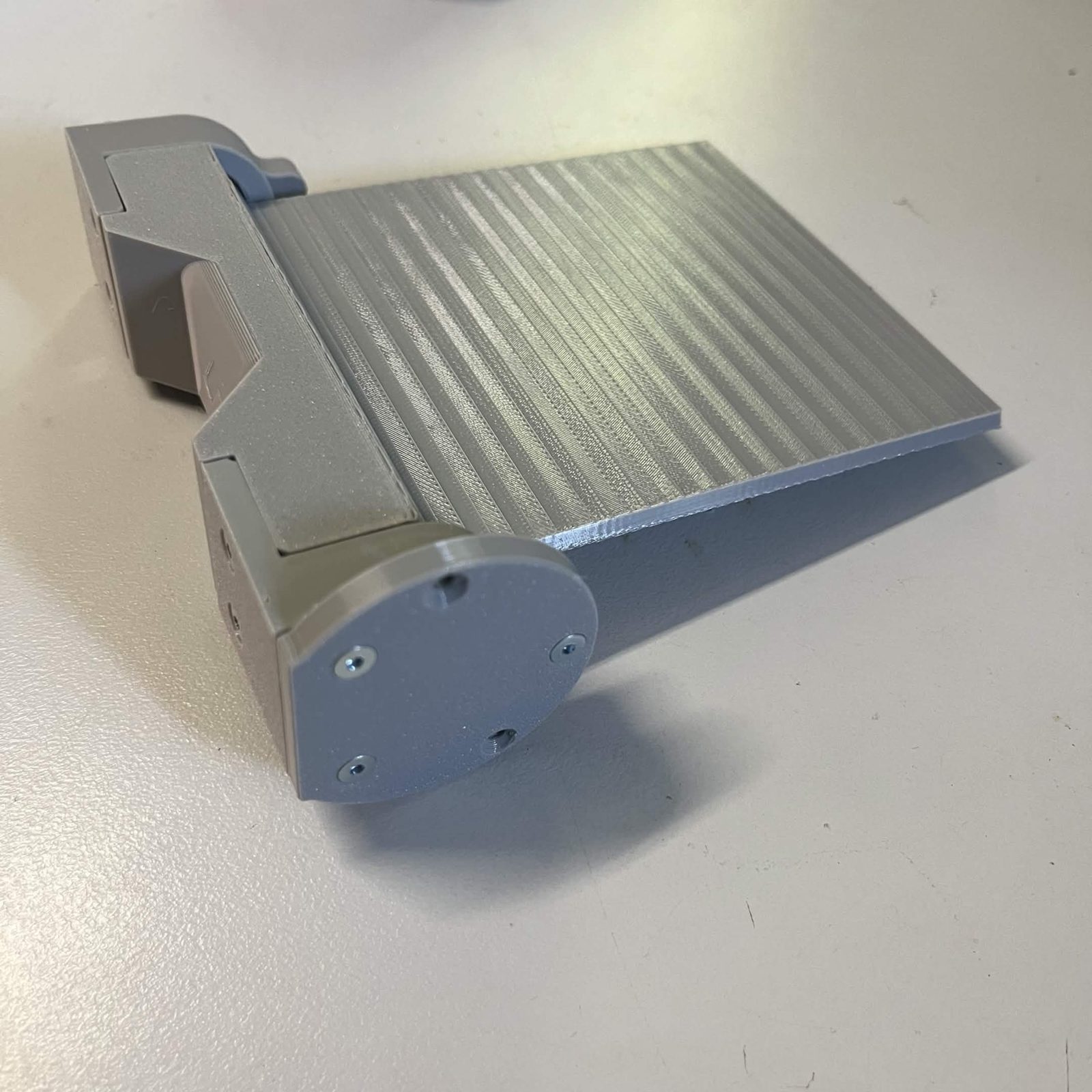 The flap assembly with a round bearing cover fitted on the near end, its screws driven around the rim, the door plate running away to the right