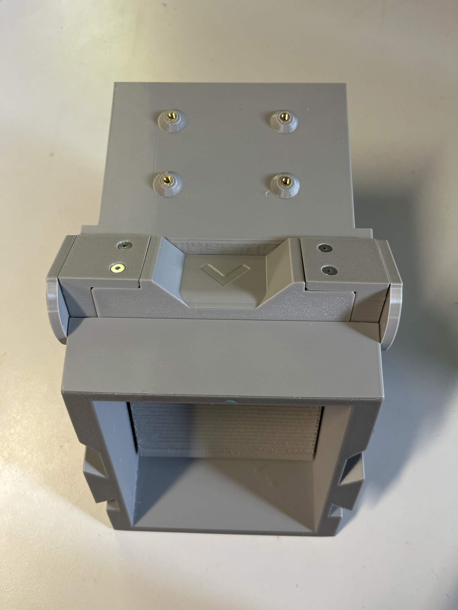 The assembly end on from the back with the door closed, four brass inserts in the flat top plate and the bearing race with its chevron sitting between the two holders
