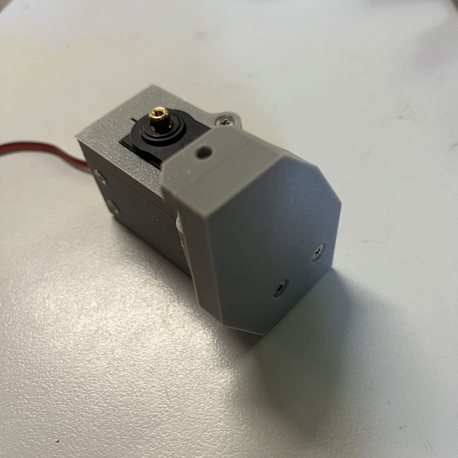 The same assembly from the servo output end, with the side arm's two screw heads sitting flush in their countersinks and the servo's splined output above them