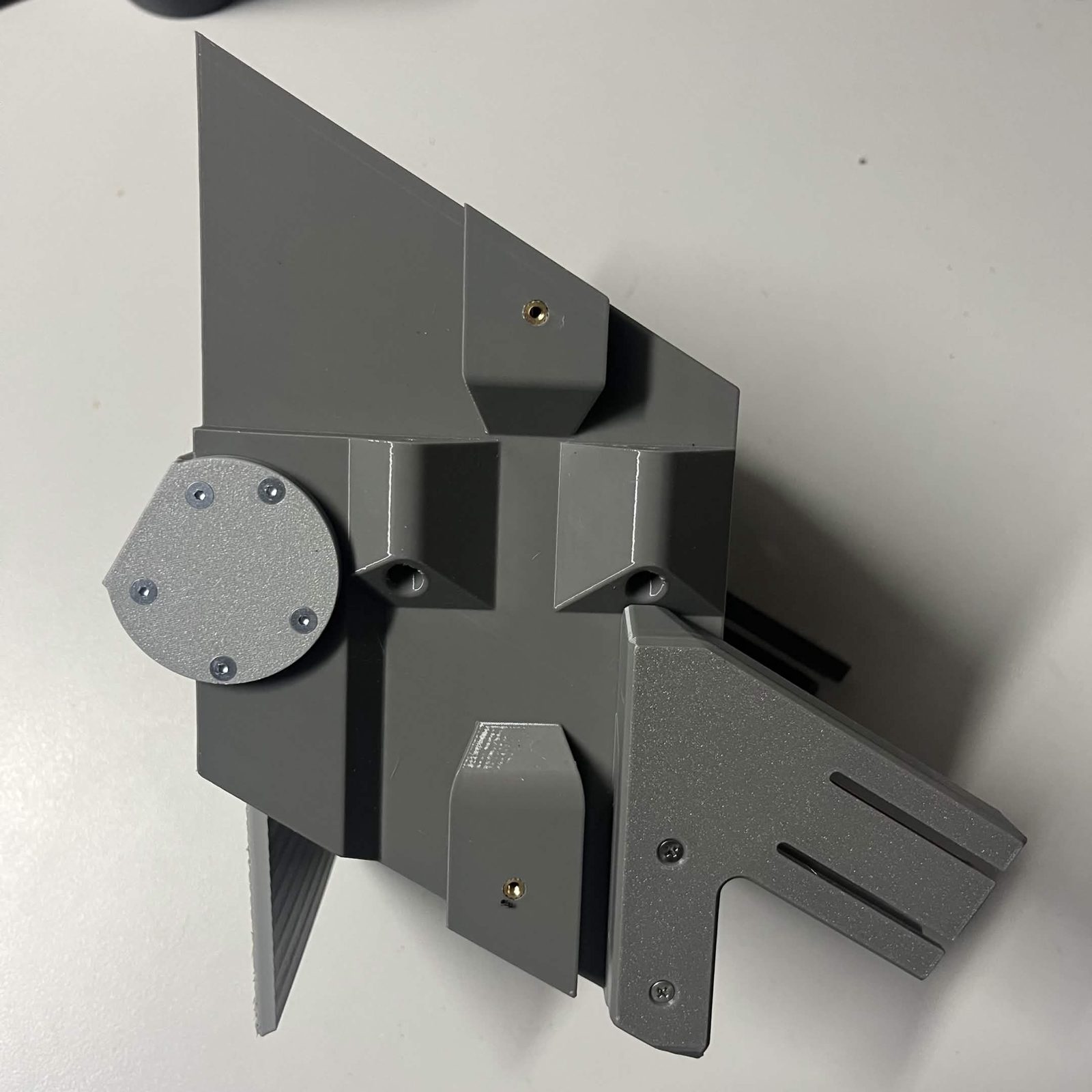 A chute core on the bench with a funnel bracket bolted to its near side, the bracket's two slotted arms standing clear of the core and its two countersunk screws driven home, the second bracket visible behind it