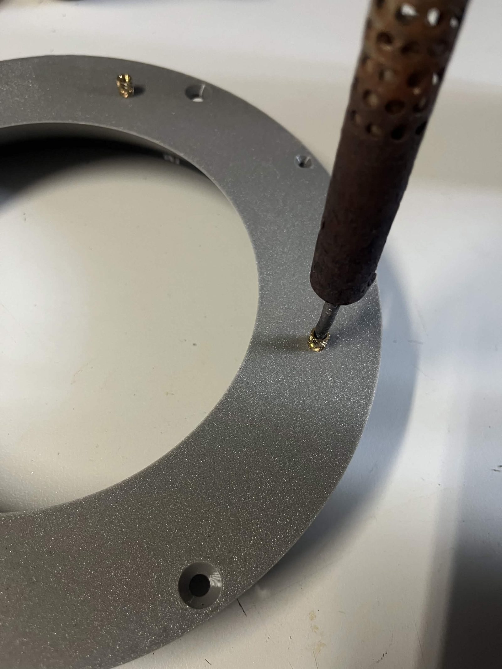 Soldering iron tip centered on a heat insert, pressing it straight down into the part