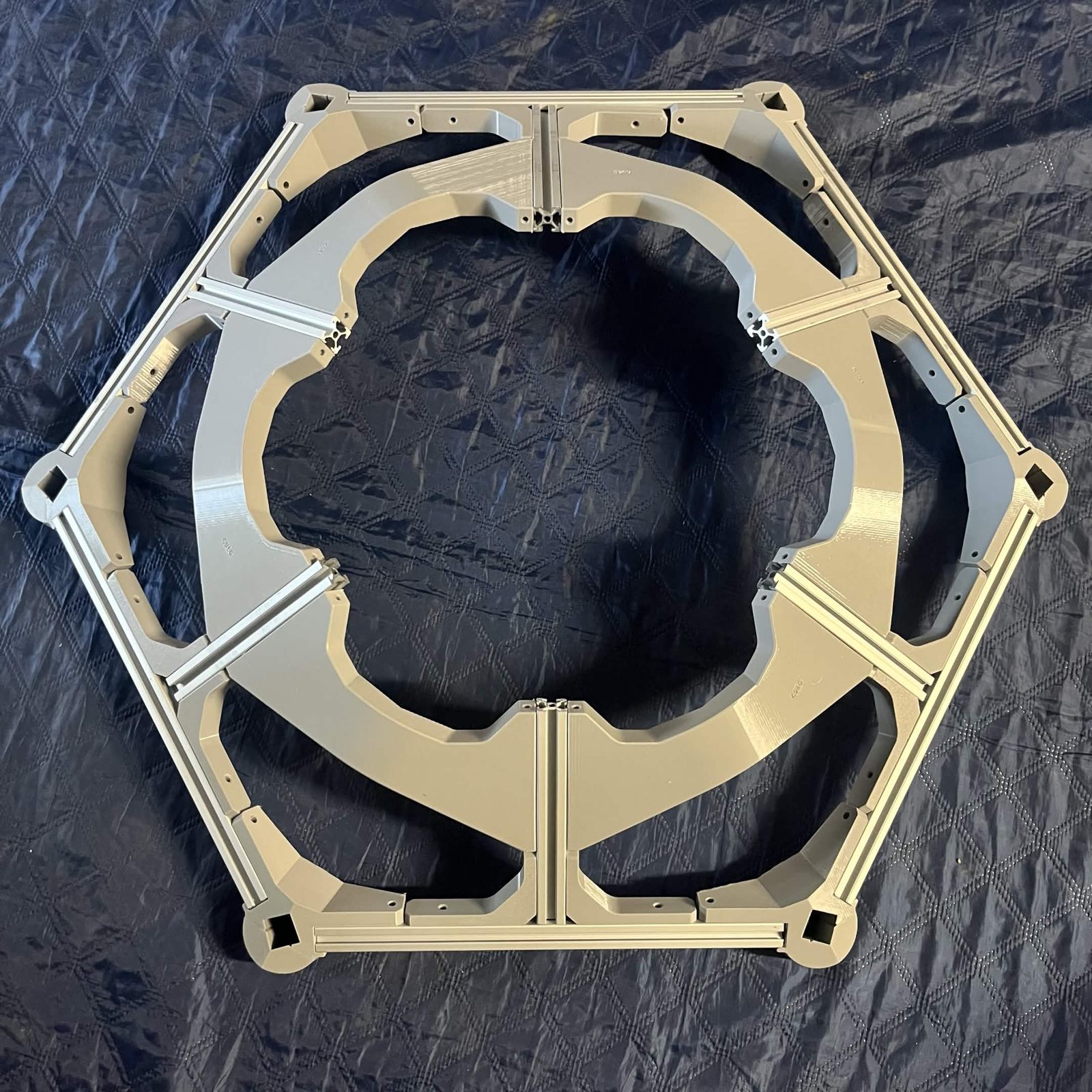 A finished hex frame from above: six B spokes and their printed crossbeams forming the inner ring inside the aluminum outer hexagon, with a printed corner bracket at each of the six vertices