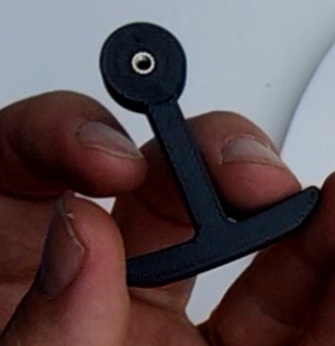 The Limit switch hammer held up, showing a single brass M3 heat insert in its round disc
