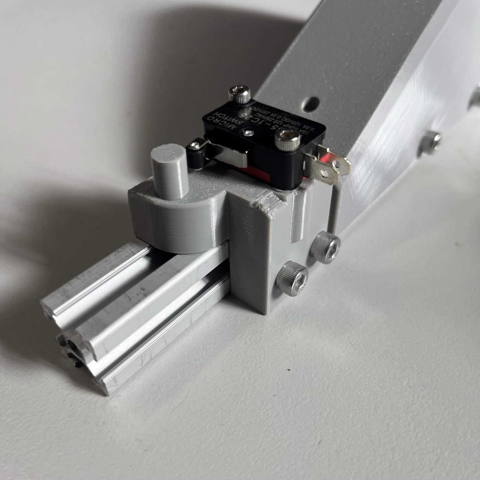 Close view of the limit switch housing on the extrusion, with its two M5 screws and the switch facing the same way as the sloped side of the bracket
