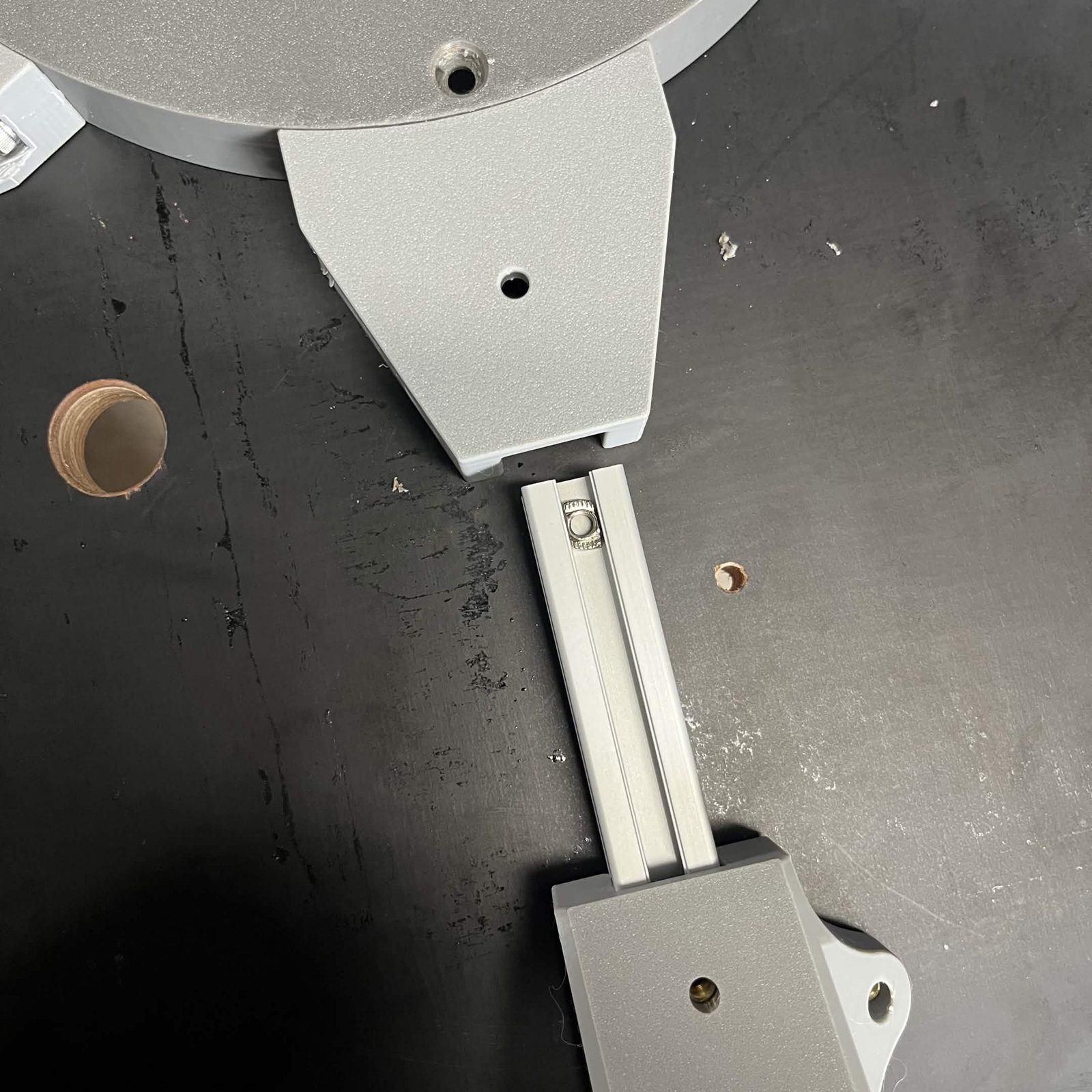 A bracket's extrusion slid into an Interface rib on the underside of the Top plate, held by a single screw