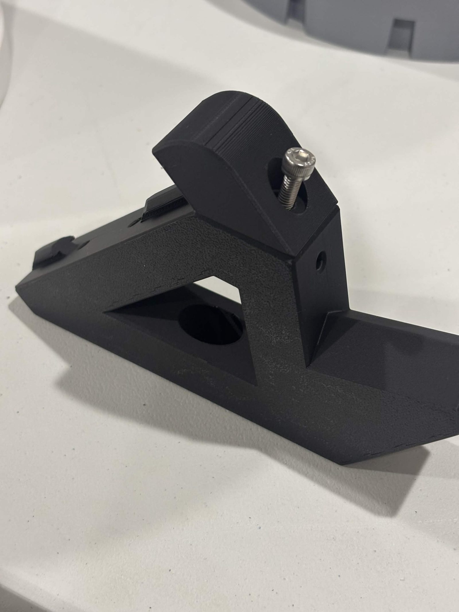 A Lazy Susan extrusion mount lying on a bench with the hold in place standing on top of it and a stainless M5 button head part way into the hole through both