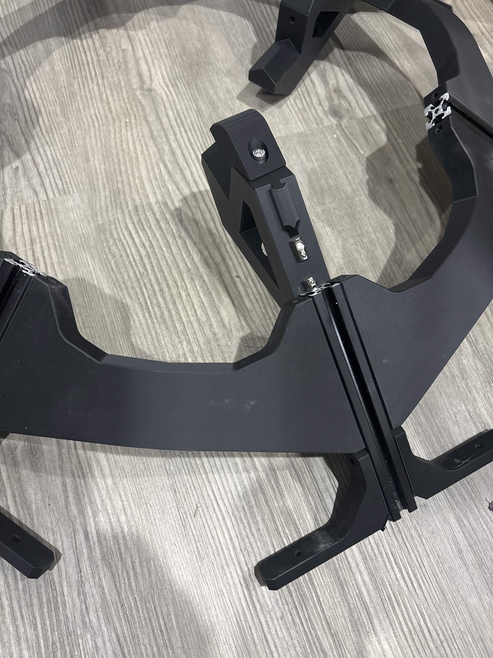 The extrusion mount sitting in position along a spoke of the hexagonal frame, with both T-nut screws still standing proud