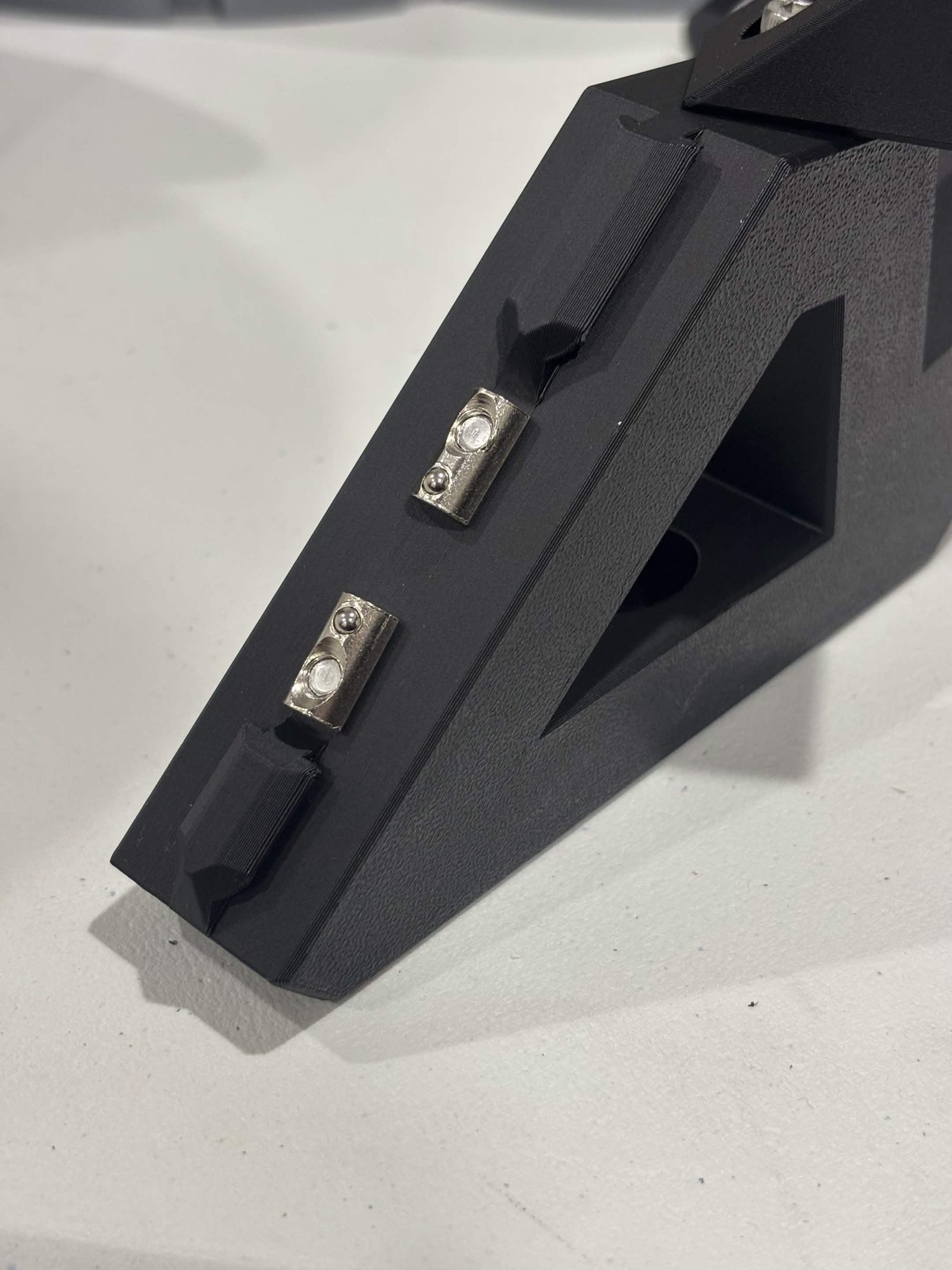 The mounting face of the extrusion mount, with two roll-in T-nuts started on screws and standing proud of the surface