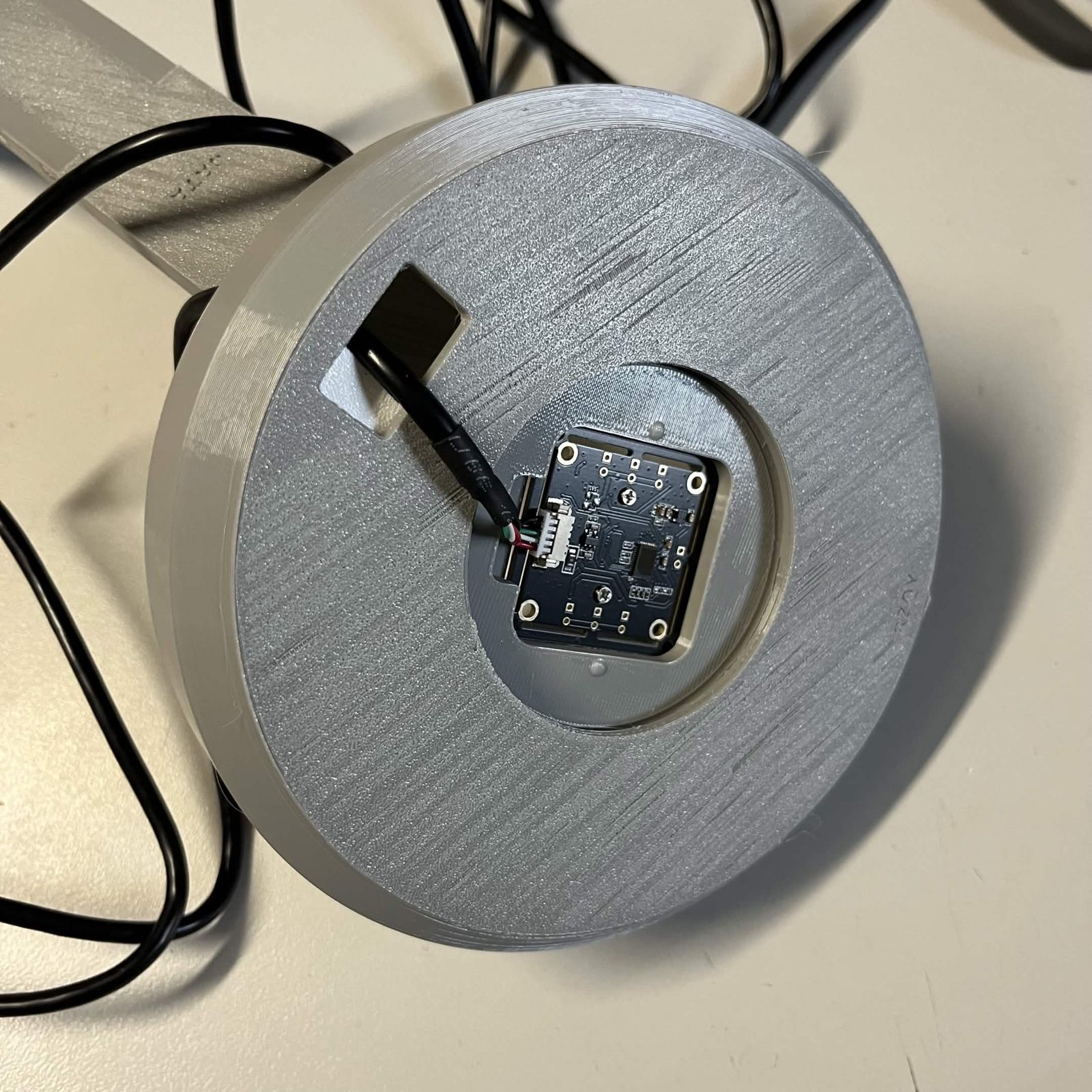 The finished lamp from above: the grey cover seated on the reflector, the camera clasp recessed in the central opening, and the cord coming up through the rectangular slot in the cover