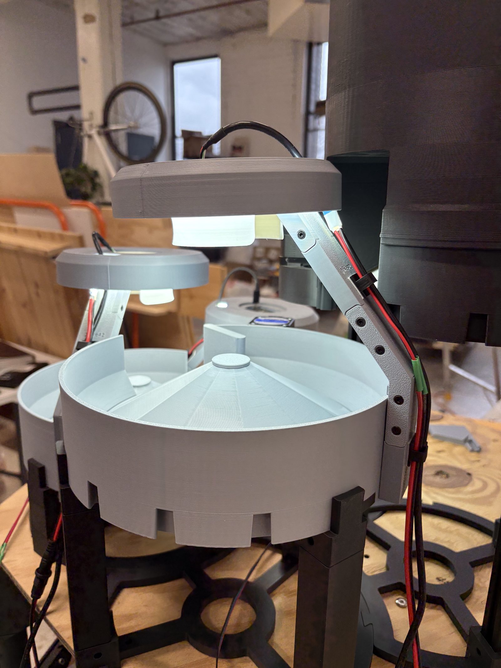 A wider view of a camera lamp on the machine, showing the full length of the arm from the lamp down to the C-channel, with a bracket screwed along the joint and the LED leads cable-tied along the arm