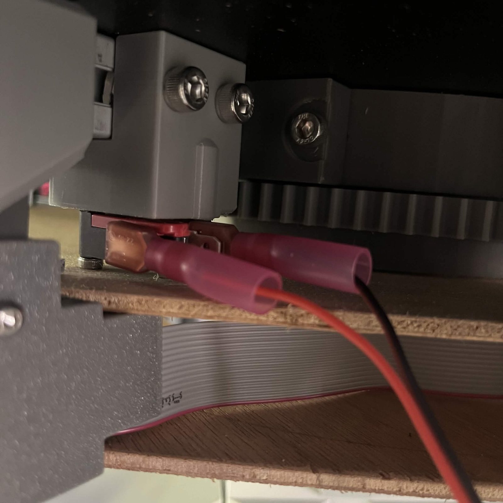 The same switch mounted under the machine's top plate in its printed housing, both insulated receptacles pushed on and the red and black pair leaving them and running away under the plate
