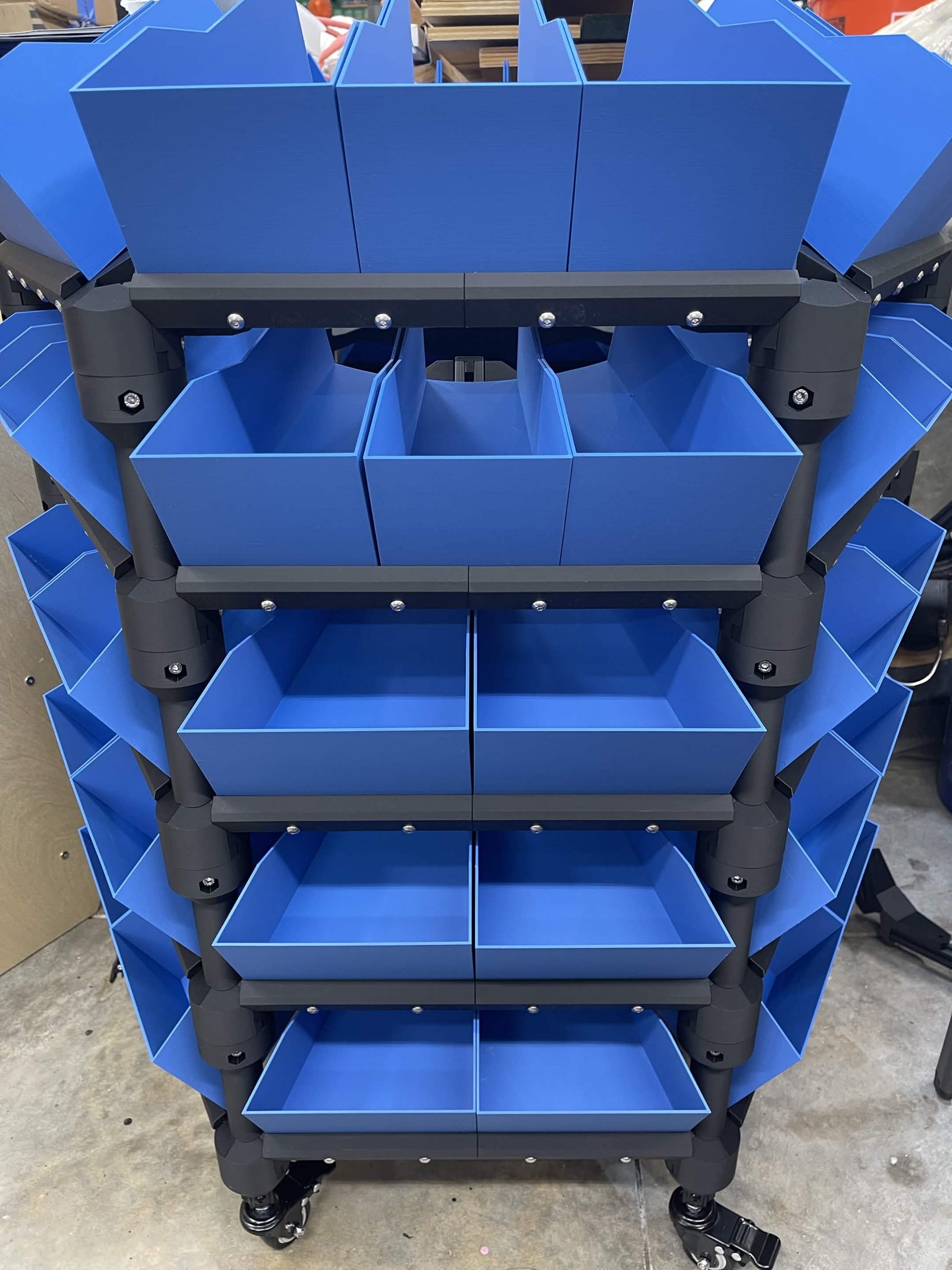 A five layer distribution stack on casters, every bay filled with blue 3D printed bins: three across on the top two layers, two across on the bottom three