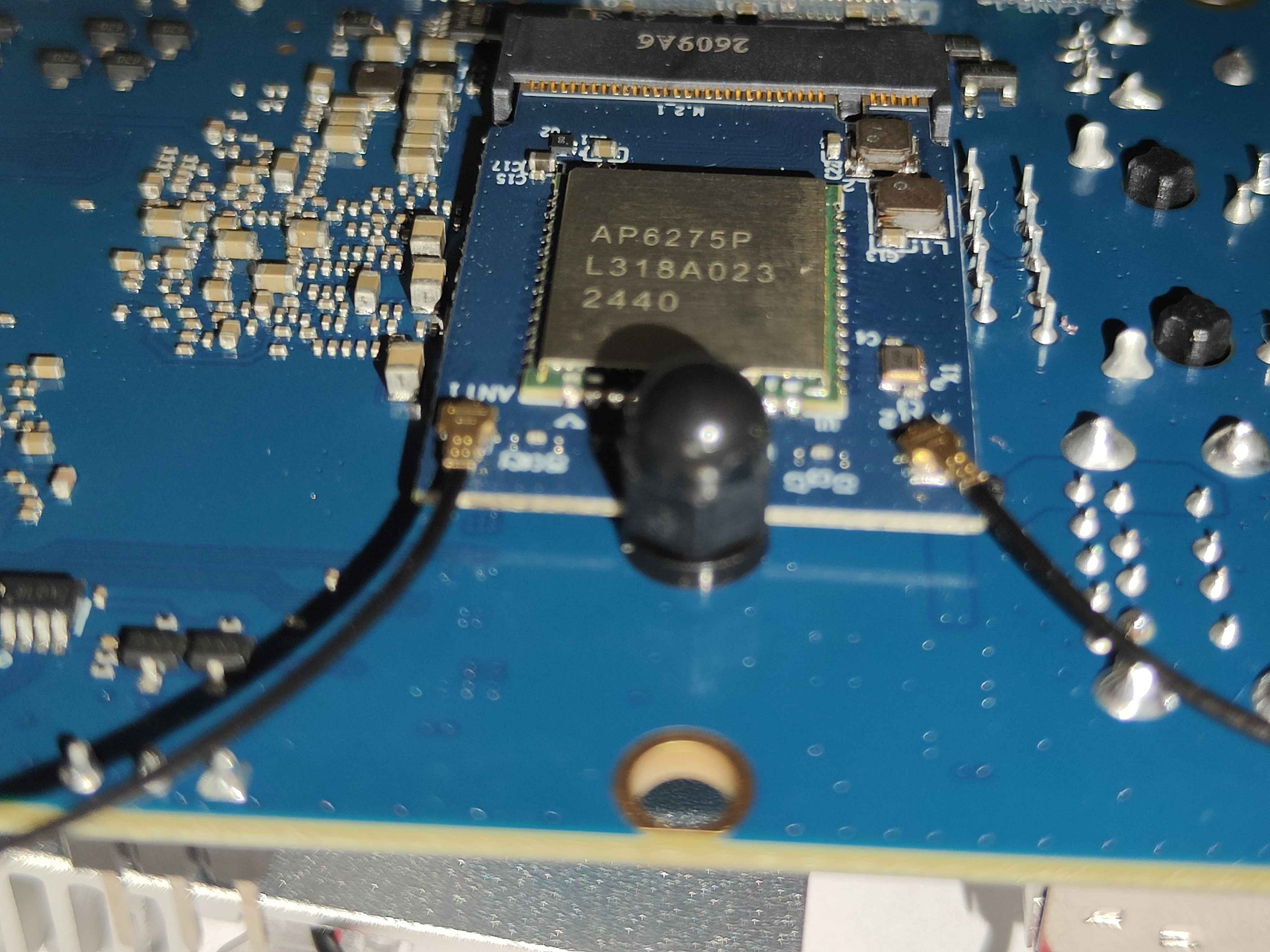 A close-up of the module's face on the underside of the board: the shielded can marked AP6275P, a black dome nut standing on the module just below it, and a gold antenna socket with a lead clipped on at each side
