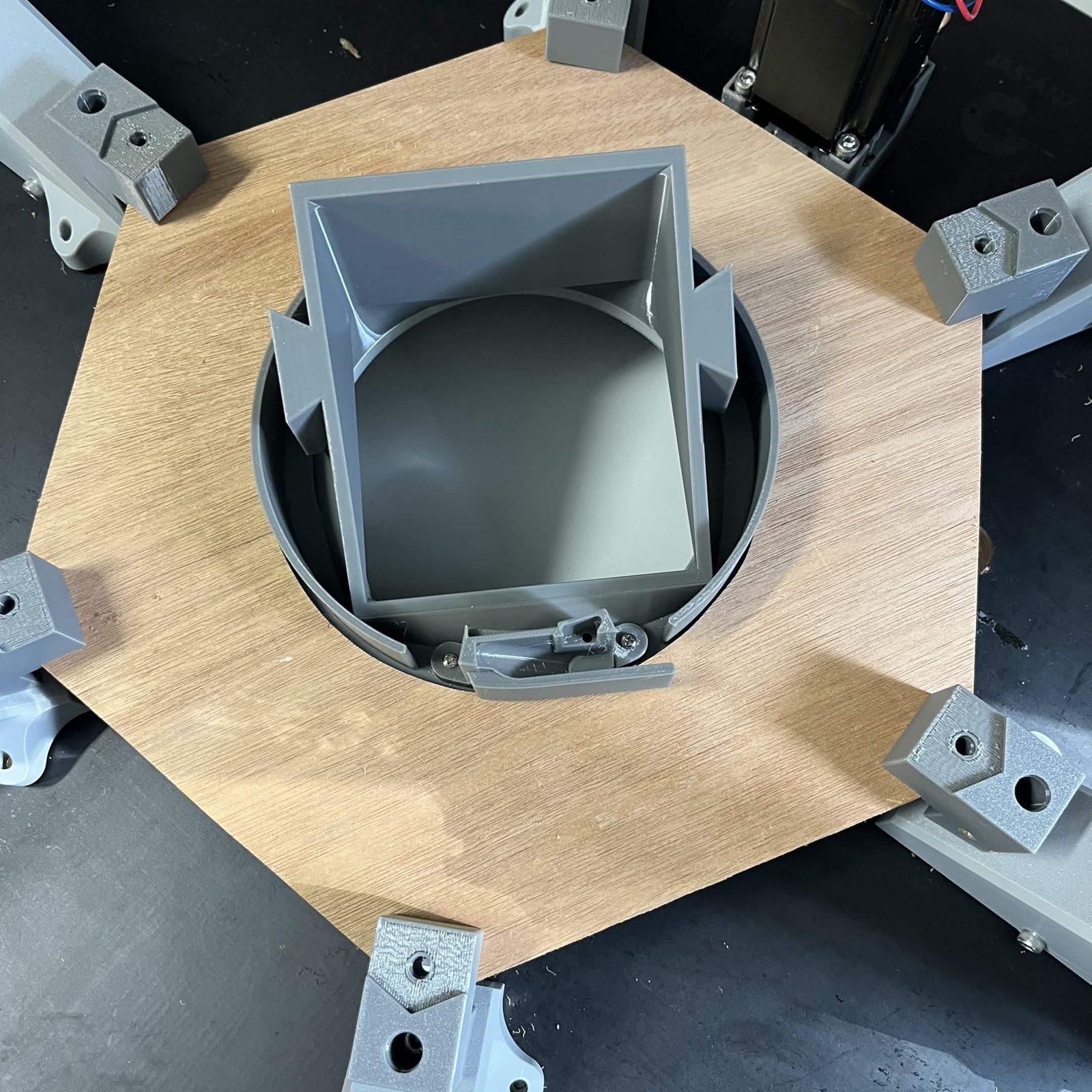 A wider view of the plate in place with all six brackets around it and the cable clamp at the near edge of the centre hole