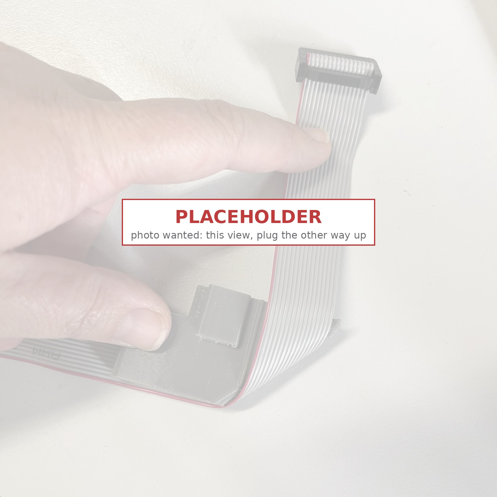 Placeholder: a faded photo of the folded ribbon cable with its IDC plug, marked PLACEHOLDER, captioned photo wanted, this view with the plug the other way up