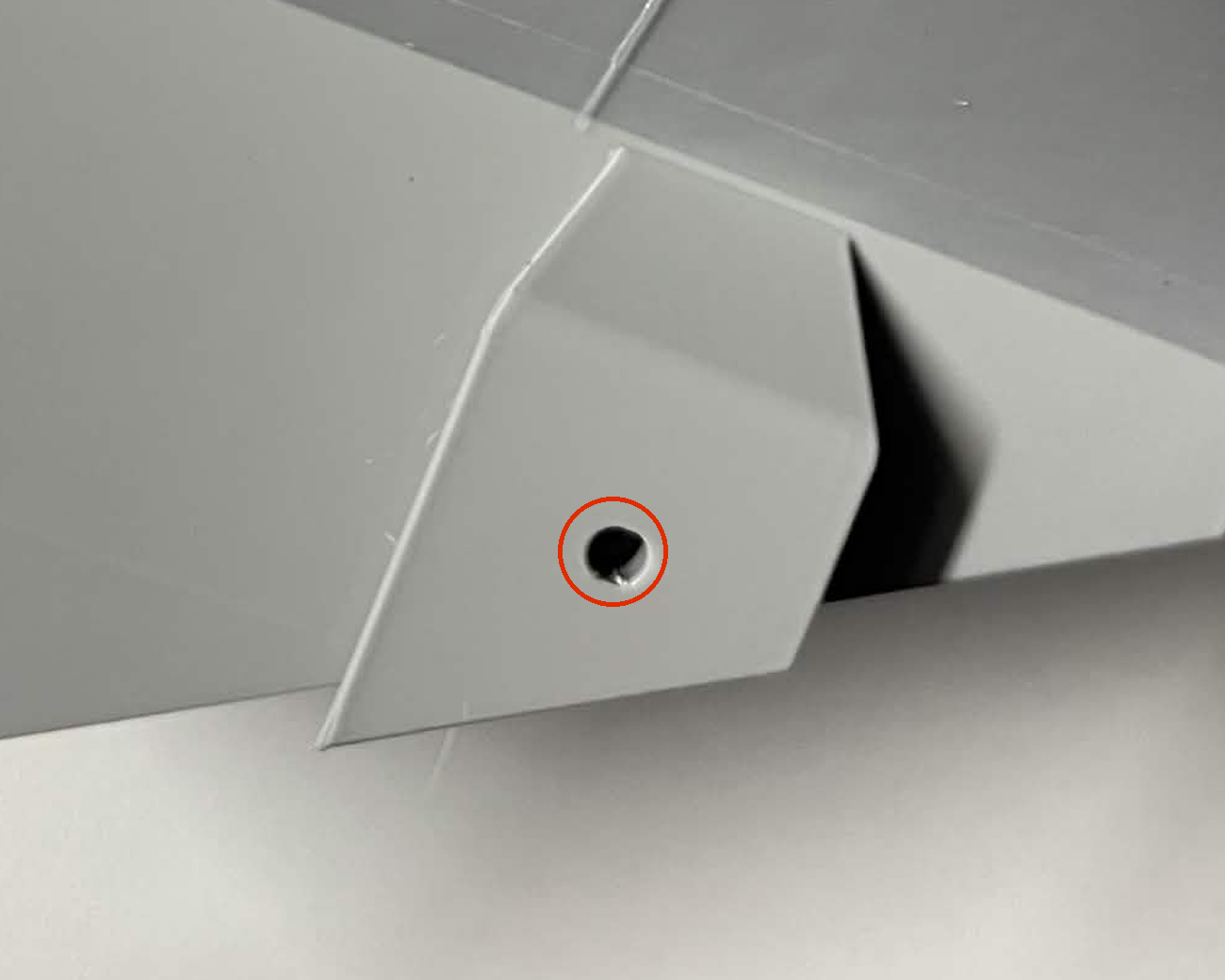 Close photo of the same raised tab on a printed chute mount, with a red circle around the empty pocket in it
