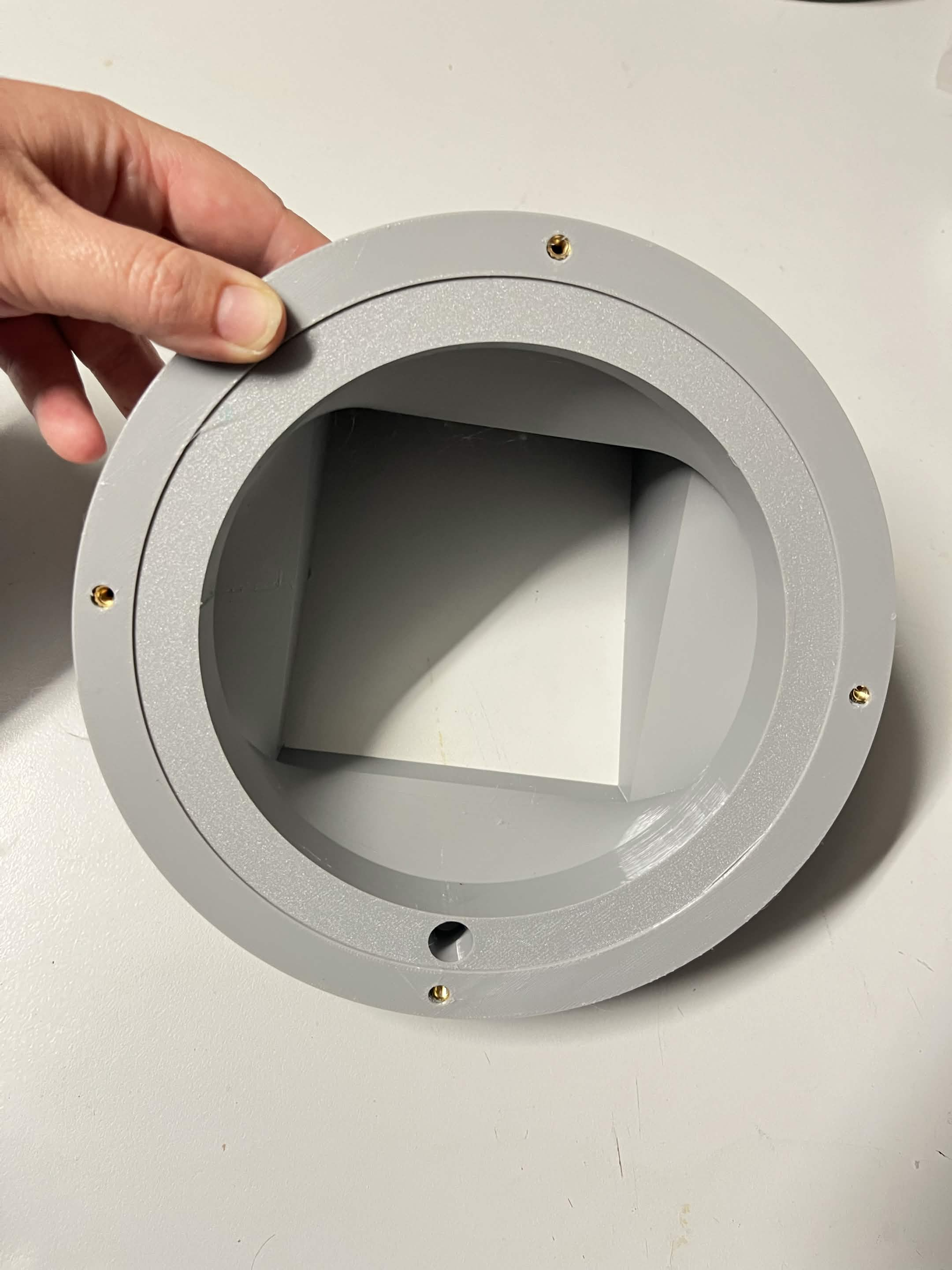 A thumb holding the Lazy Susan washer in place on the chute mount, before the bearing goes on top