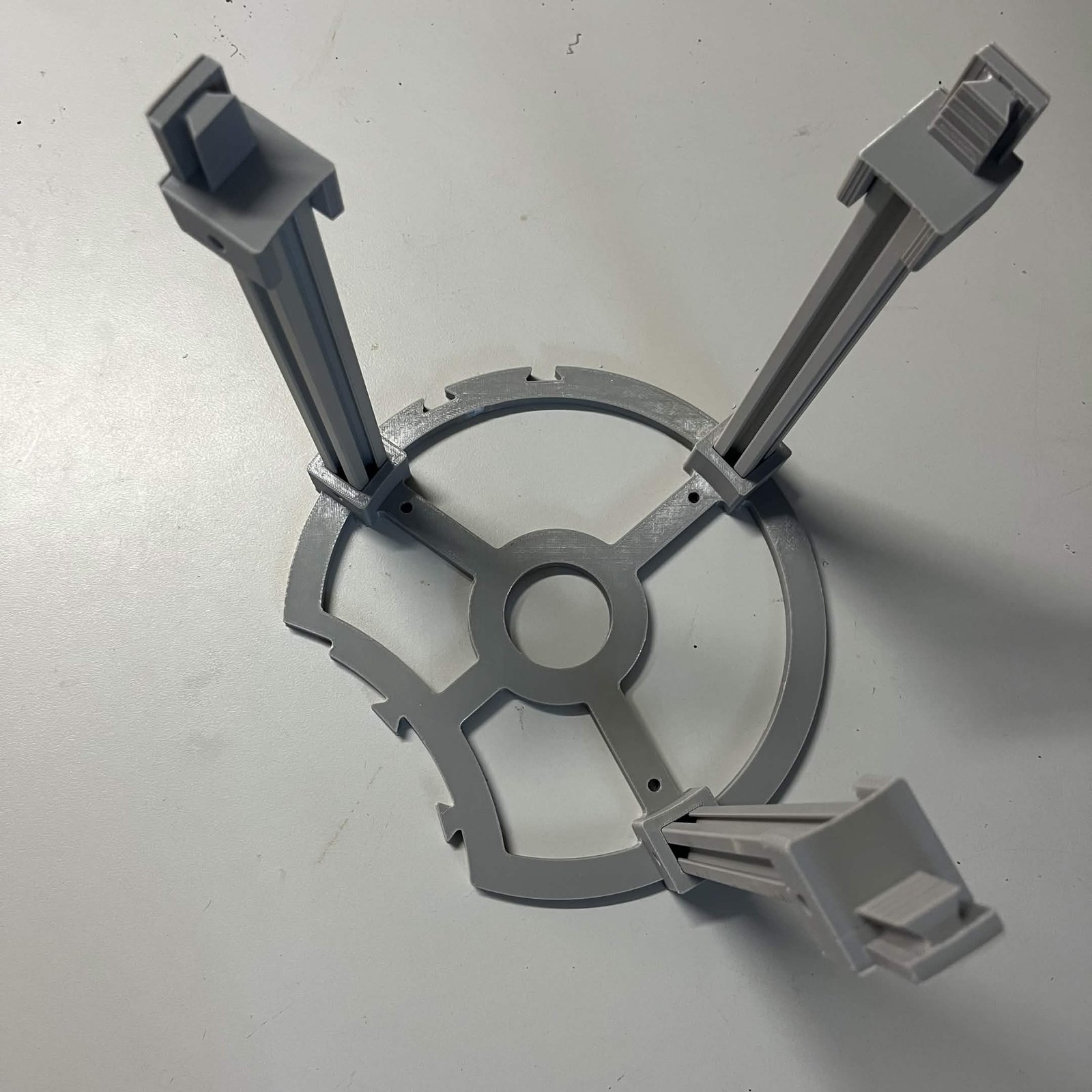 C1's stand: the layout guide flat on a bench with three 2020 aluminium extrusion legs standing in its sockets, each capped by a printed dovetail adapter