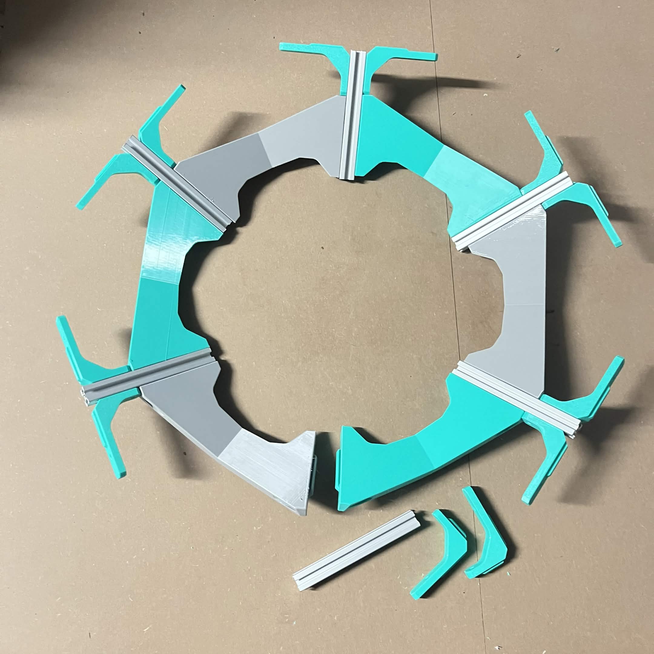 The near-complete spoke ring with a Frame 90 degree bracket pair at five of the six spoke junctions, two spare brackets and the loose spoke sitting at the open sixth junction
