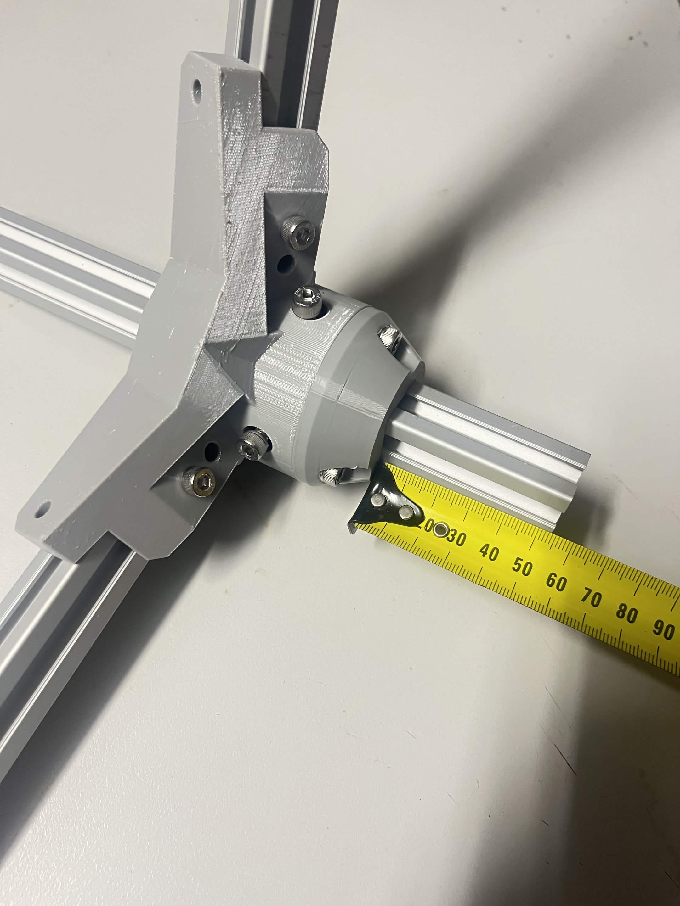 Piece D held against the bracket with a tape measure alongside, measuring from the bottom before the collar screws are tightened
