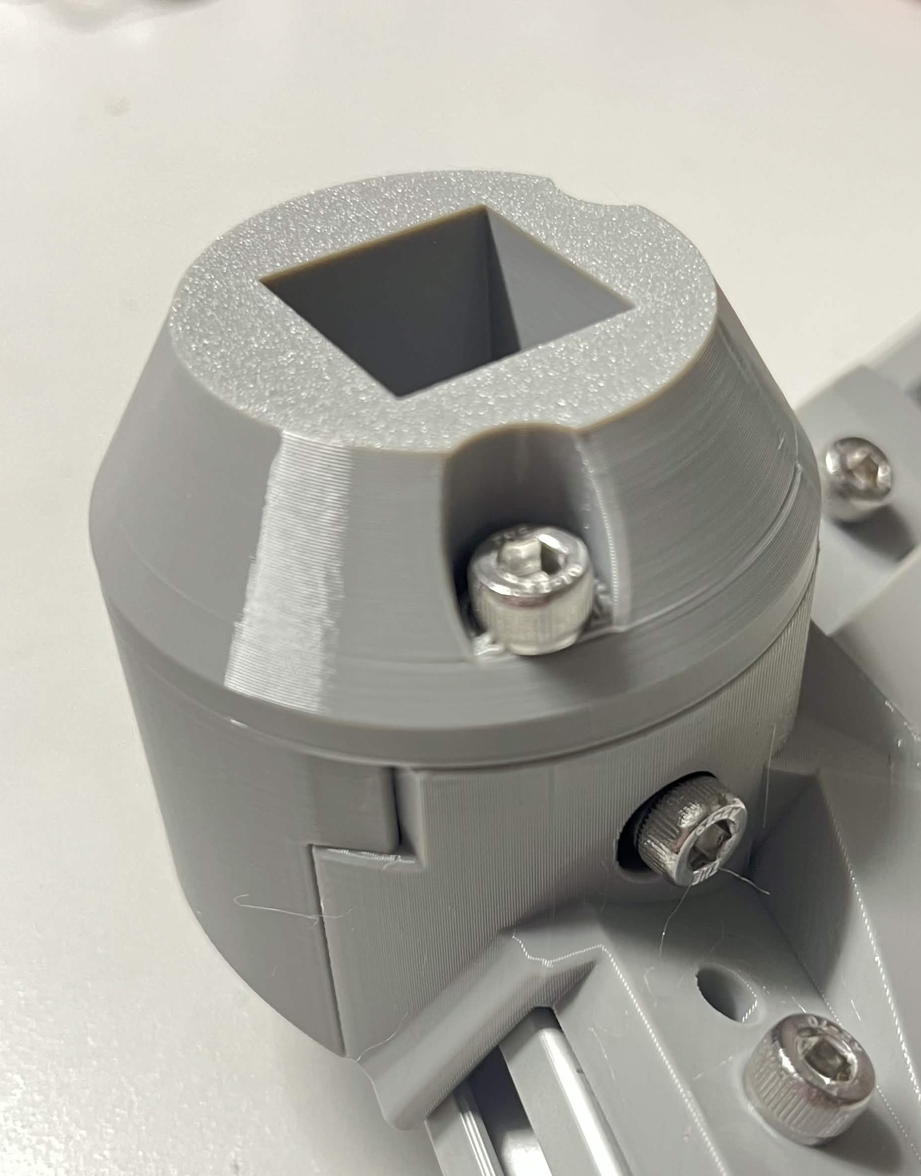 Close-up of the foot cover bolted to the External bracket — side, with the two foot-cover screws and the extrusion mounting screws visible